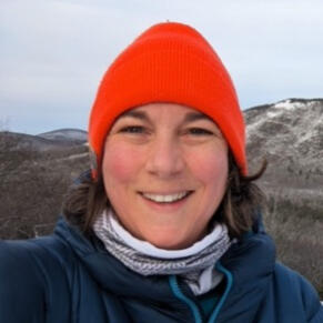 Photo of woman wearing orange hat with snowy natural hills in the background